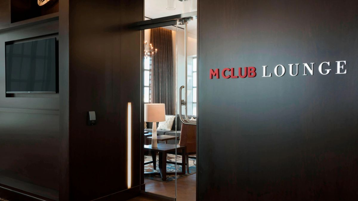 Entrance to a Marriott M Club Lounge with glass doors, modern décor, and lounge seating in the background.