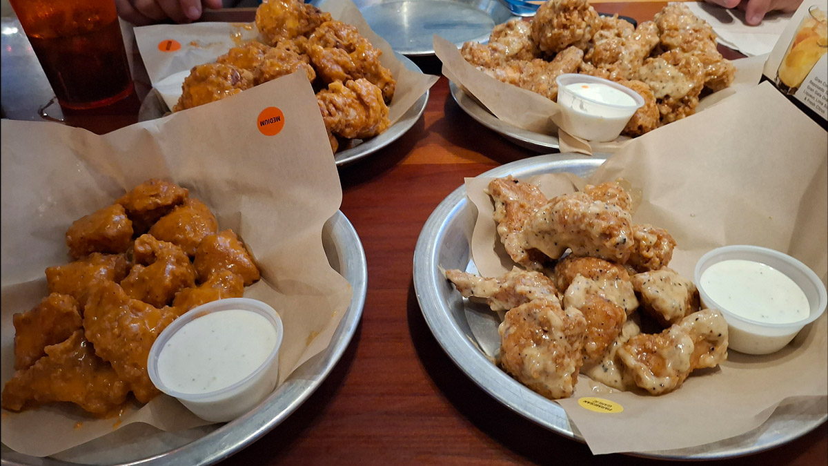 Plates of classic and boneless chicken wings served at Hooters ONE Daytona, a popular spot for casual teen-friendly meals